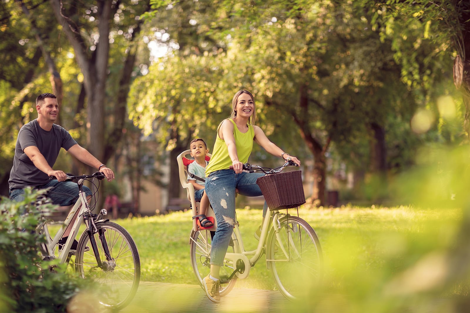 Family riding bikes in a park.